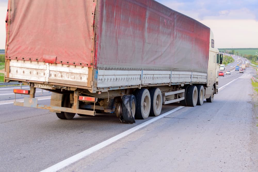 A damaged semi-truck with a blown tire on the roadside, illustrating big-rig crash investigations.