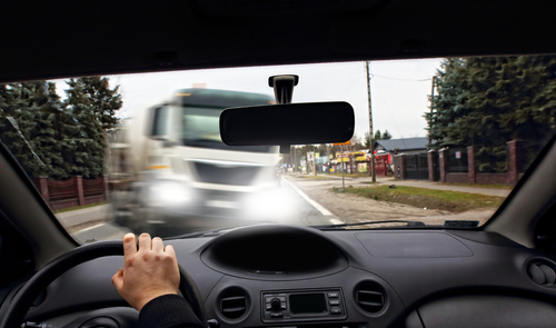 The view from inside a car as the driver approaches an oncoming truck, highlighting the importance of safe driving practices to avoid collisions.