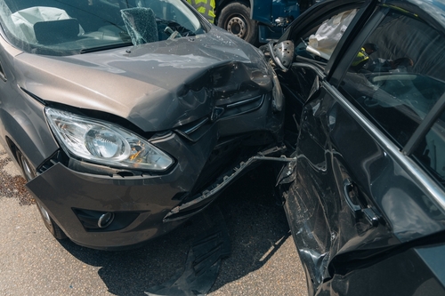 Two heavily damaged cars after a collision, with visible crumpled front ends, indicating a serious car accident.