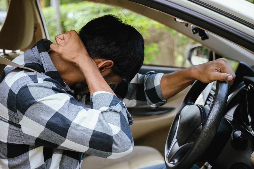 Driver clutching neck in pain after an accident, illustrating the need for legal assistance.