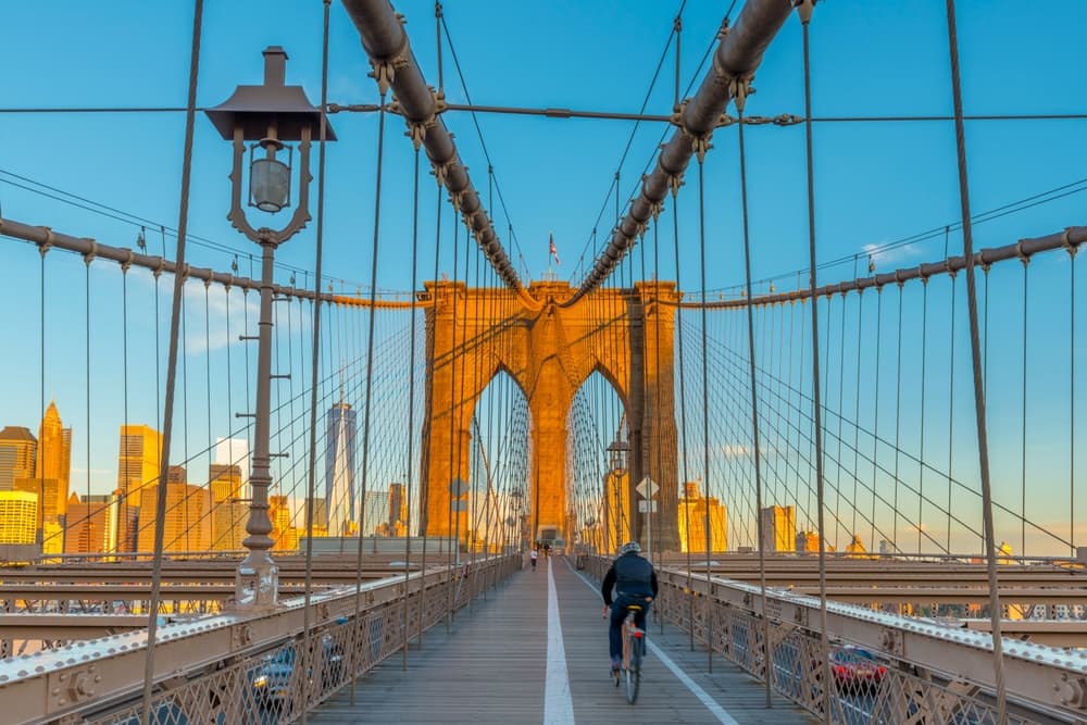 The iconic Brooklyn Bridge spanning the East River, with the Lower Manhattan skyline in the background, including the Freedom Tower of the World Trade Center, New York, USA.