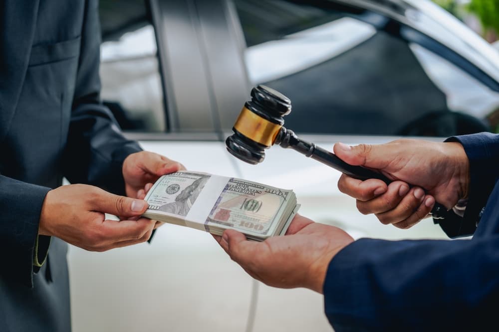 A car insurance agent next to a damaged vehicle, reviewing policy details, evaluating the damage, and completing the necessary paperwork.