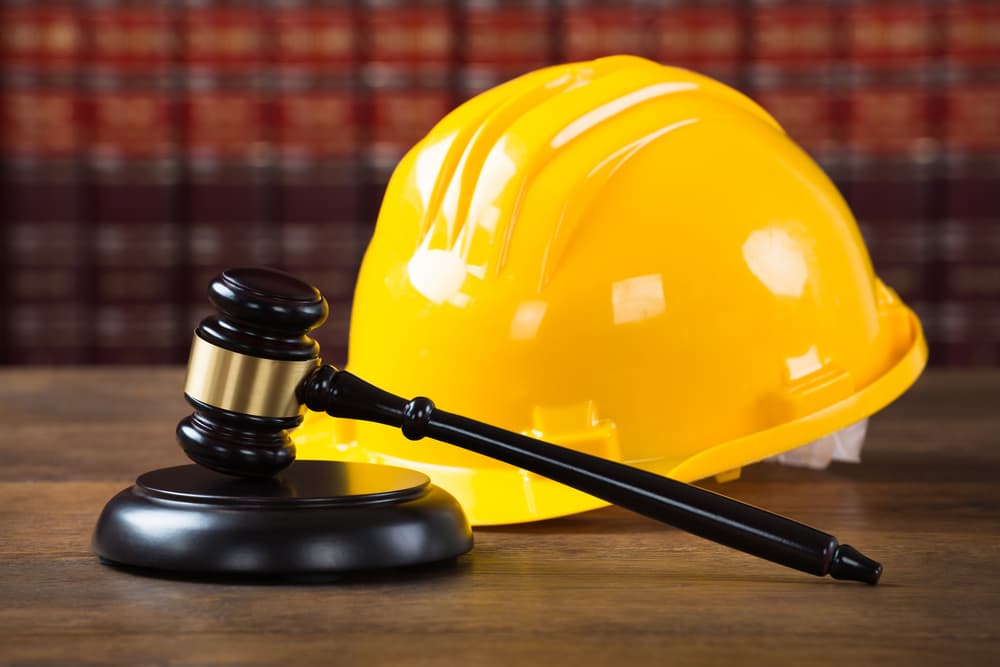 The image of a wooden mallet and a yellow hardhat on a table in a courtroom setting.