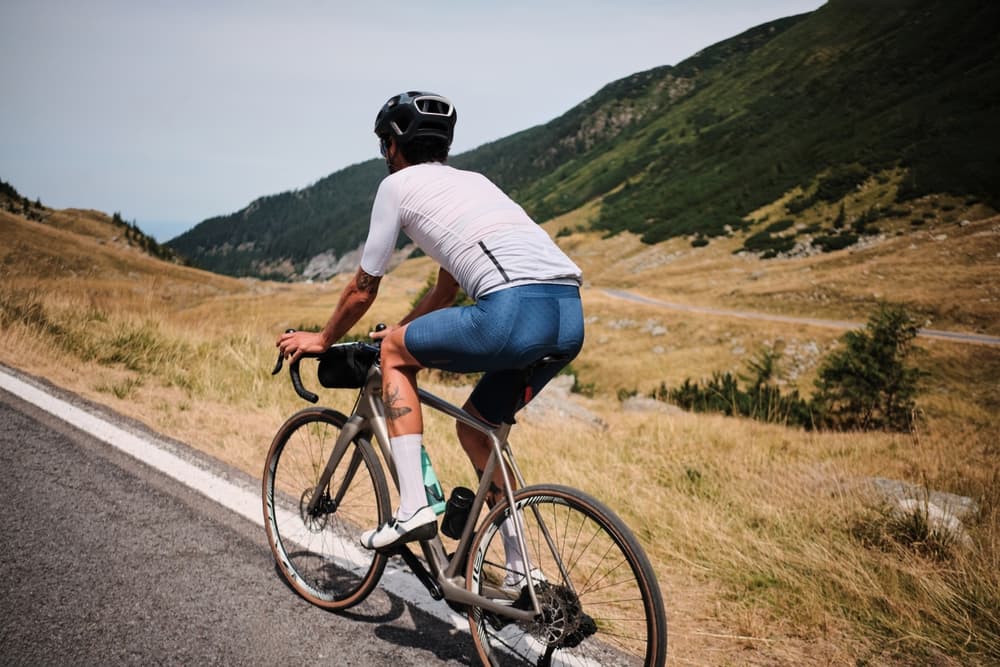 A male cyclist rides his bicycle on the winding Transfagarasan Road, surrounded by breathtaking mountain scenery.