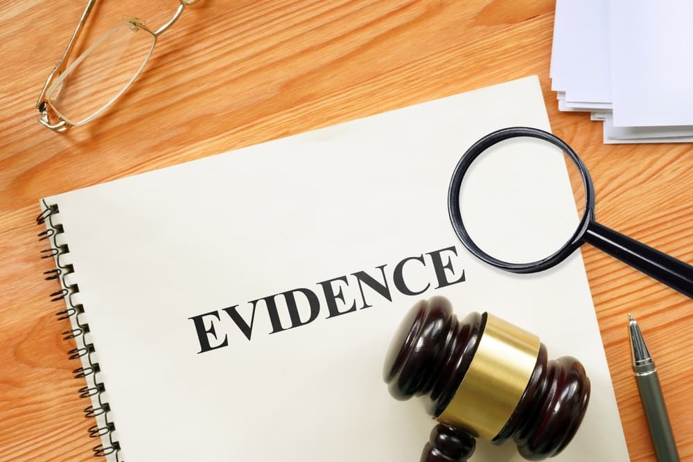 The word "Evidence" magnified through a magnifying glass on a notebook, illustrating the business and legal concept.