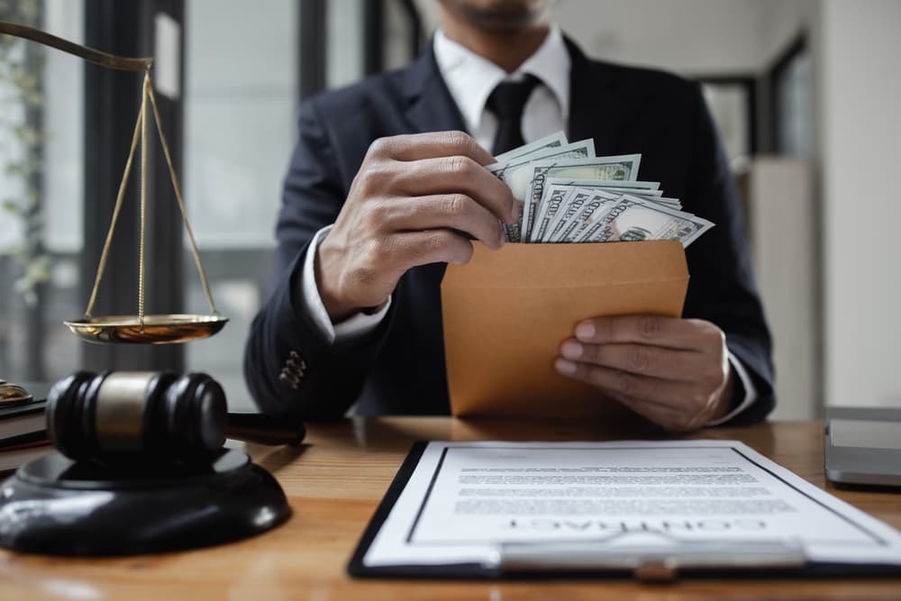 A lawyer working on a contract agreement at an office table, holding money received as contingency fees from the client, symbolizing a successful legal resolution.