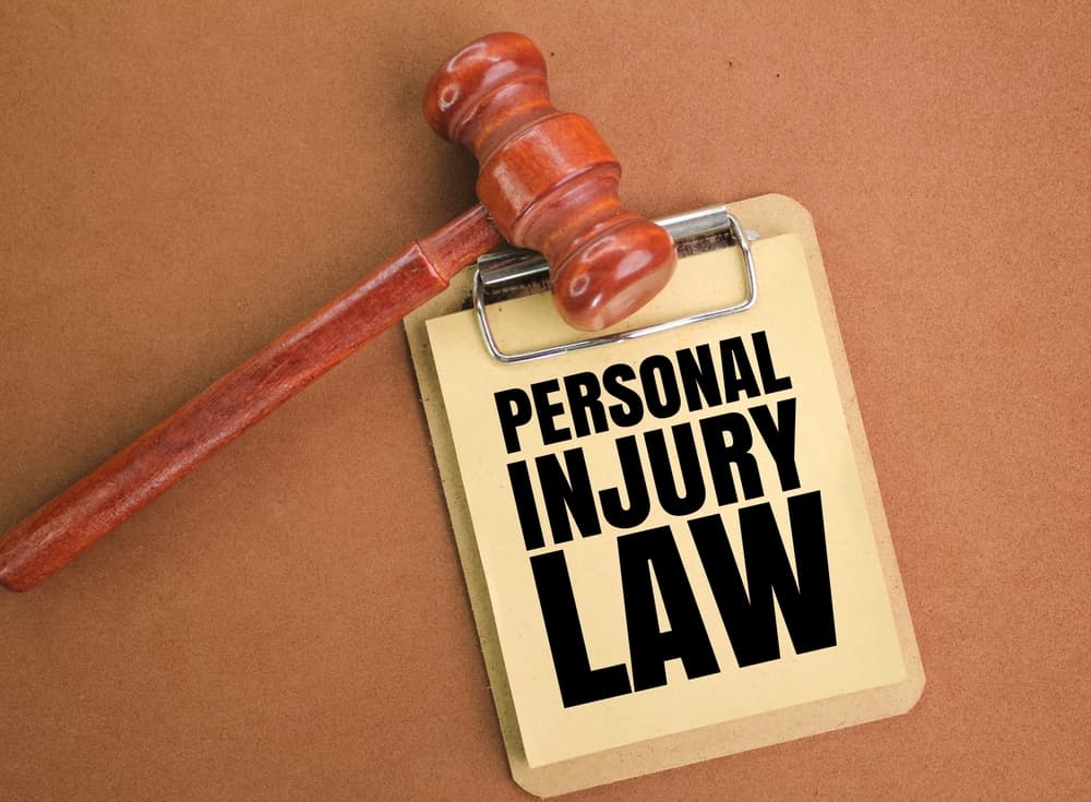 Judge's gavel placed next to a blackboard displaying the words "Personal Injury Law" written in bold. Legal concept illustration.