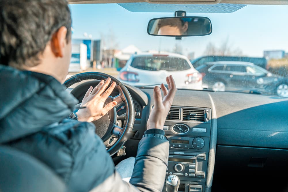 An irate man honking the car horn.