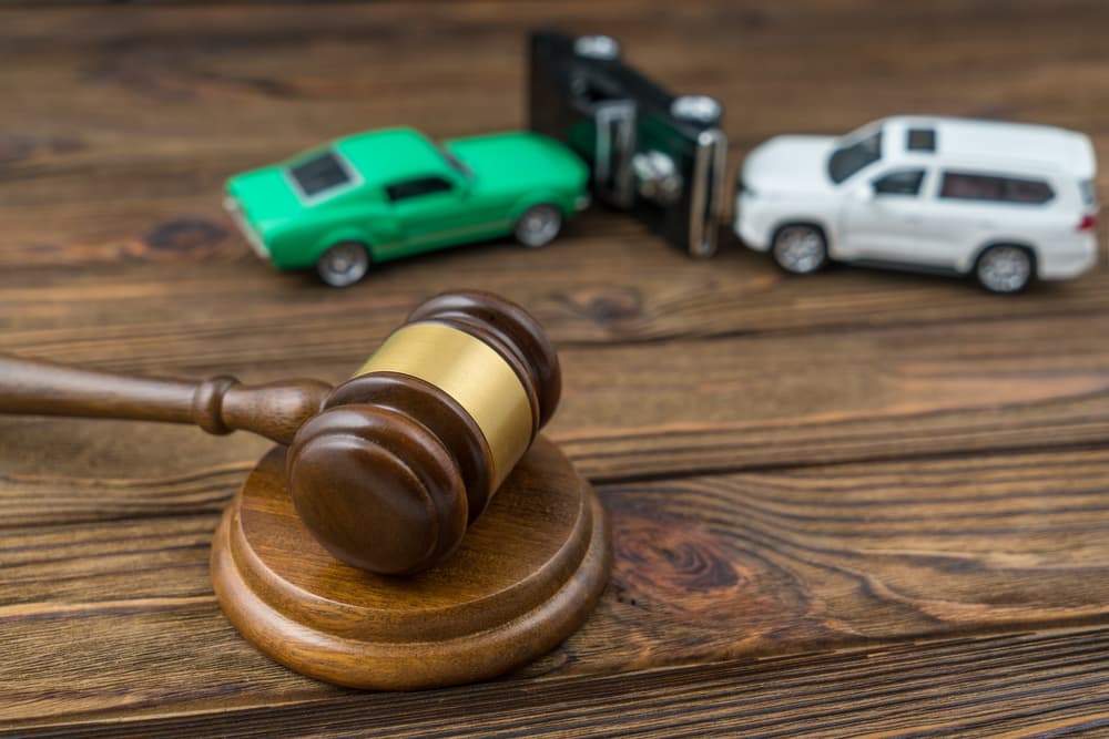 A judge's gavel with a car accident scene in the background, symbolizing traffic disputes, insurance claims, foreclosure, and determining fault.