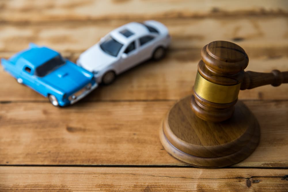 A scene depicting a car crash with a judge's gavel on the table, symbolizing legal proceedings related to the accident.