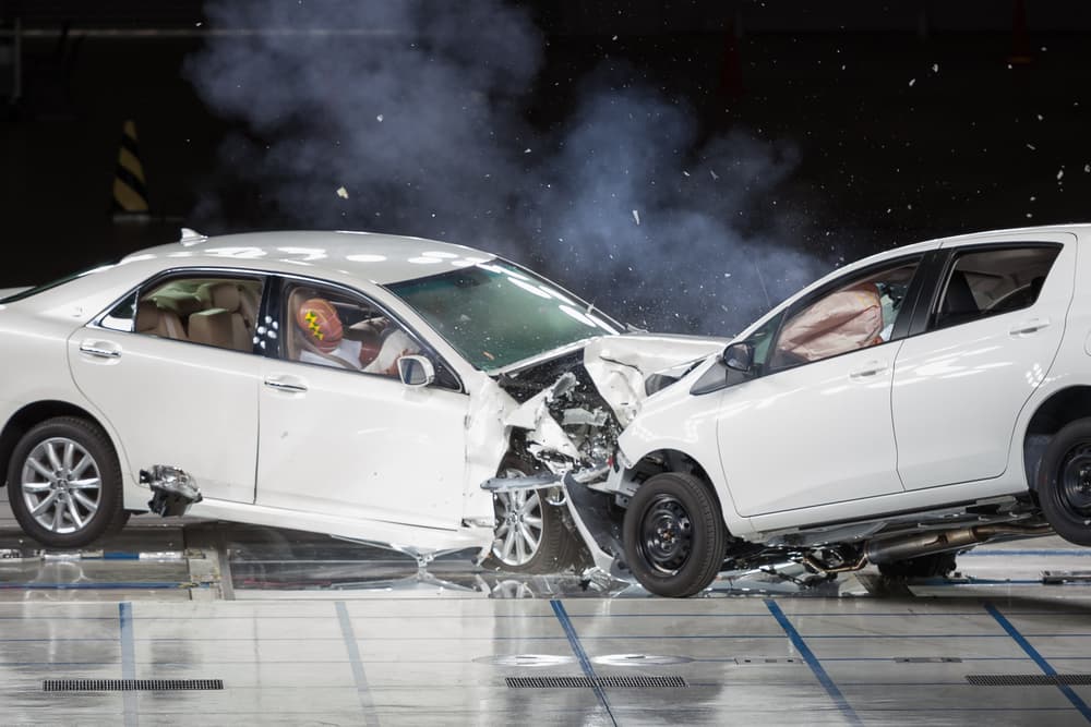 A front-end collision occurring during a crash test, with vehicles impacting head-on to assess safety and damage.