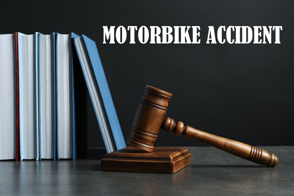 Motorbike accident law concept. A judge's gavel and legal books rest on a table, set against a dark background symbolizing justice and legal proceedings.