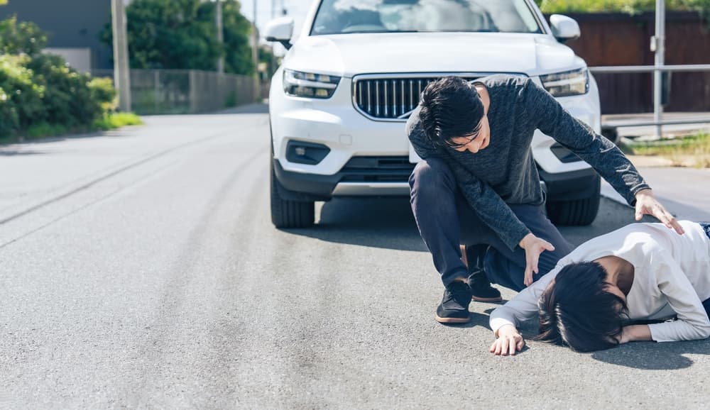 A driver is visibly panicking after causing a traffic accident, with a worried expression and hands on the steering wheel, while looking at the damage caused.