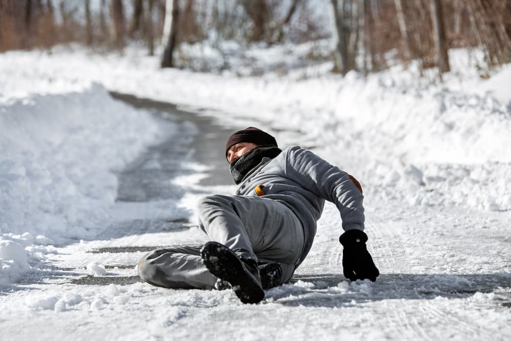 An injured man lying on the road after a fall due to black ice during the winter season.