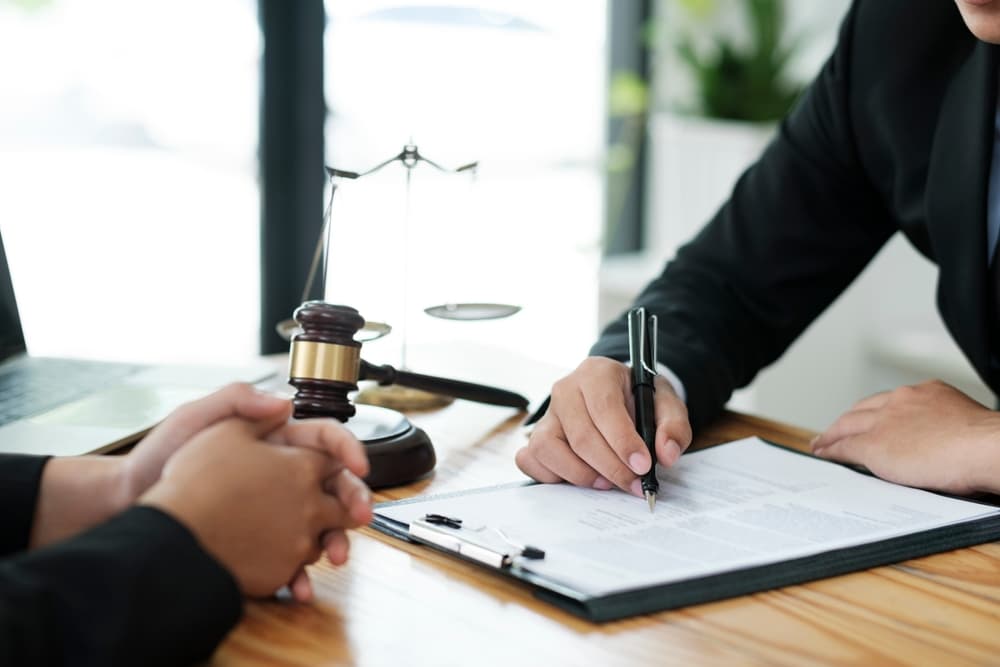 An attorney consulting with a client about their offense, explaining the case, and providing legal advice for a courtroom appearance, with a judge's gavel on the table.