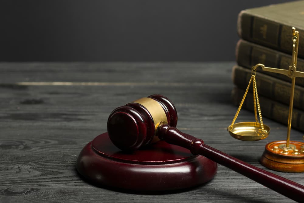 Law concept – An open law book with a wooden judge's gavel on a table in a courtroom or law office, isolated on a white background. Copy space available.