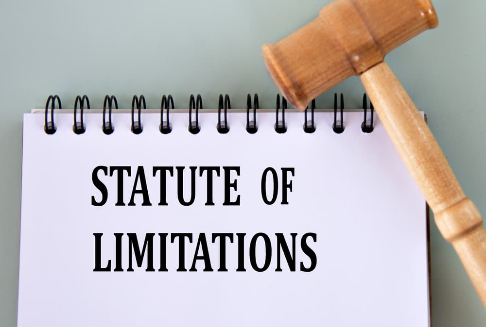 "Statute of Limitations" written in a notebook on a gray background, accompanied by a judge's gavel.