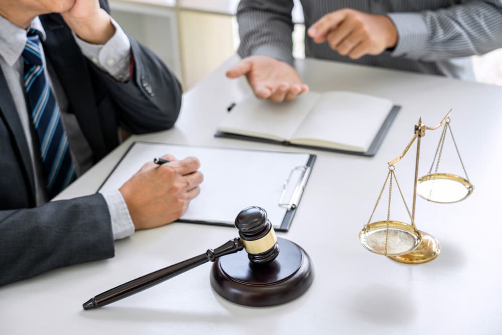 Judge's gavel with scales of justice. Businessman and lawyer consulting and discussing contract papers at a law firm office.